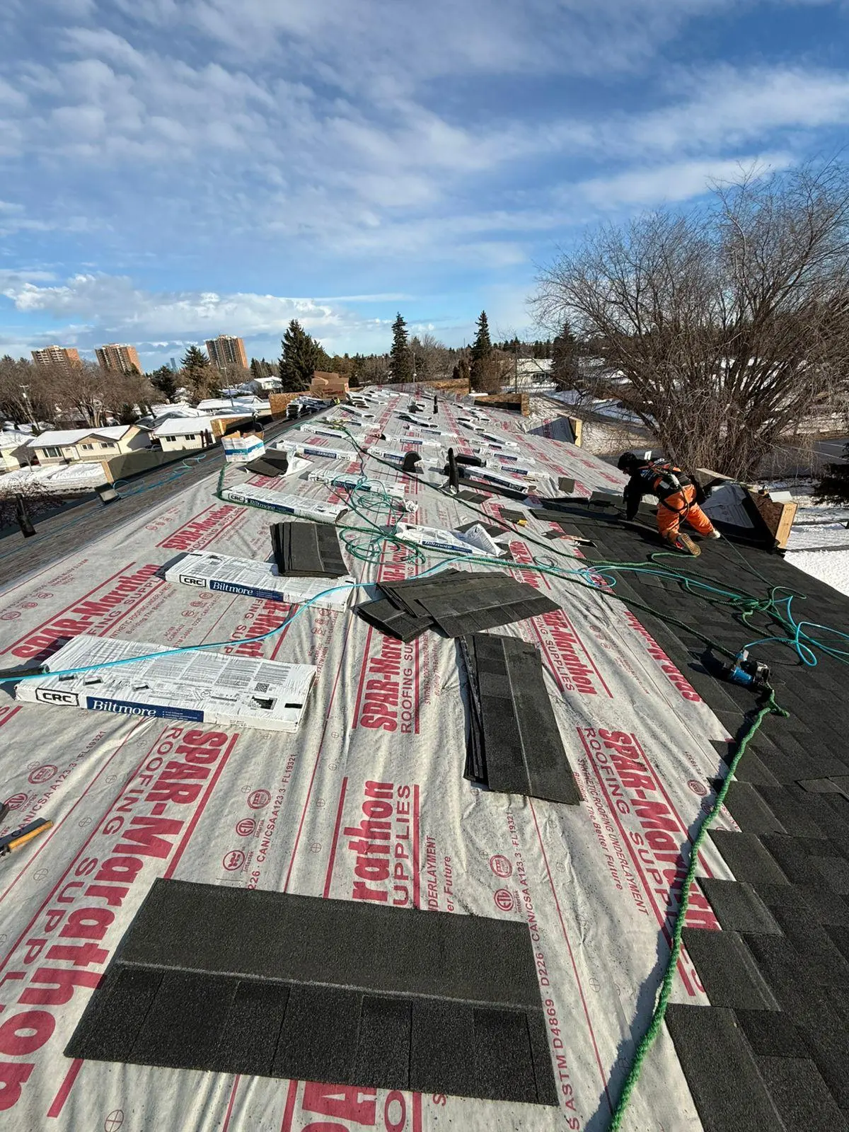 Winter re-roofing project with shingle bundles laid out